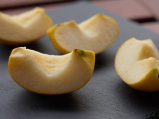 Slices of apple on stone plate on wooden table - breakfast with slices of apple - sliced golden apple