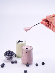 Women's hand holding a spoon with blueberry yogurt