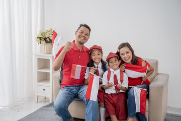 happy excited family with indonesian flag raise their arm support their sport team