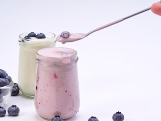 Women's hand holding a spoon with blueberry yogurt