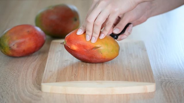 Woman hands cutting fresh mango.