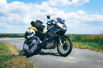 A male driver in a raincoat is sitting by adventure motorbike with side bags. a motorcycle tour...