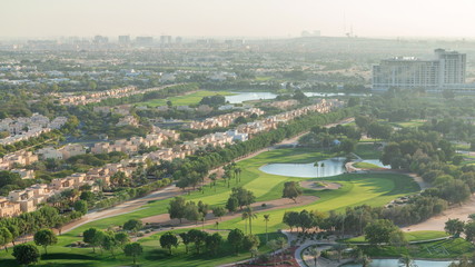 Naklejka premium Aerial view to villas and houses with Golf course with green lawn and lakes timelapse