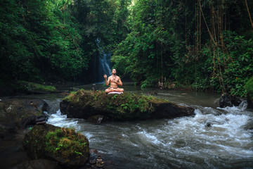 Yoga practice and meditation in nature. Man practicing near river