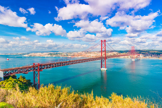 The 25th April Bridge (Ponte 25 de Abril) in Lisbon, Portugal. Picturesque skyline with beautiful sky