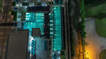 Modern swimming pool aerial view night timelapse from above beside a green lawn golf course