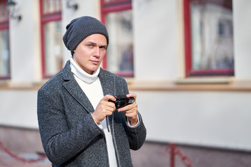 Modern urban hipster trendy man wearing a fashionable gray coat, white sweater and gray hat with...