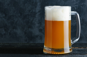Glass mug of wheat unfiltered beer on the background of a concrete wall in the pub with copy space