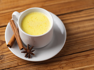 Golden milk with turmeric on wooden table