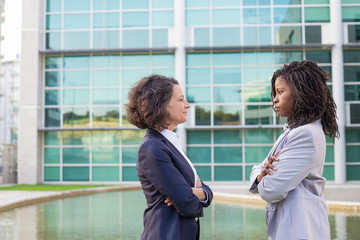 Confident businesswomen meeting outside. Two women wearing office suits, standing against each...