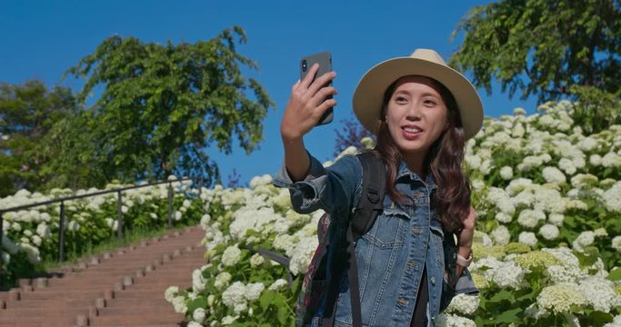 Woman take selfie on phone with white Hydrangea flower garden