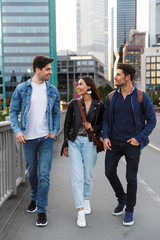 Fototapeta premium Cheerful happy optimistic young friends walking outdoors by street in city.
