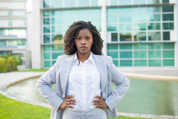 Confident determined businesswoman posing outside. Young black woman wearing formal suit, standing...