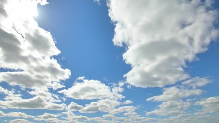 Airplane flying in the blue sky among clouds and sunlight
