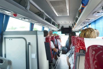 tourist trip in the bus with people, blue curtains, luggage racks