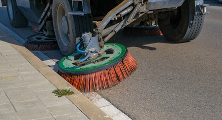 Sweeper truck industrial vehicle cleans urban road the streets of the city. Fragment of a street...