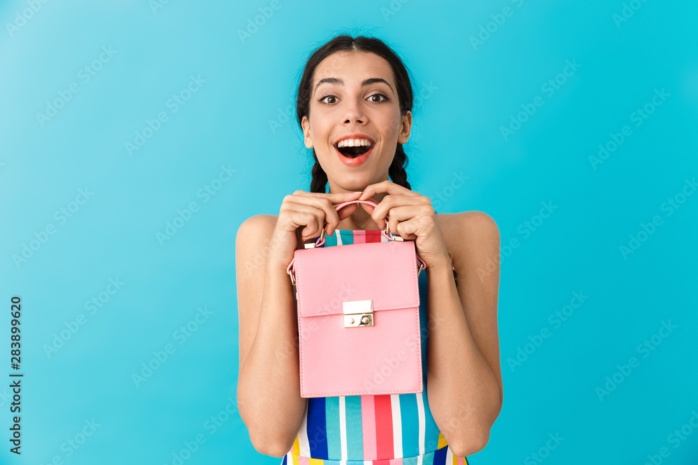 Wall mural Image of pleased delighted woman with pigtails holding pink bag and smiling