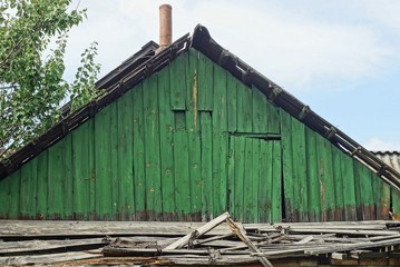 old green wooden loft with the door of a rural house on a background of sky
