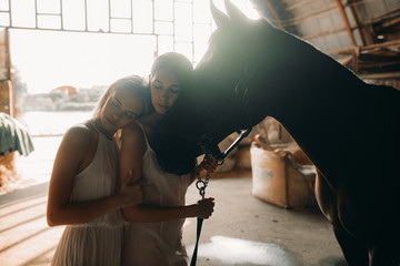 Two women stand next to a horse.