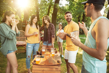 Group of happy friends having beer and barbecue party at sunny day. Resting together outdoor in a...