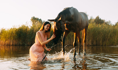 Woman sits next to the horse that produces splashes on the water.