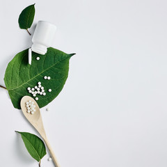 Homeopathy, naturopathy and alternative herbal medicine. Bottle with homeopathic pills on green...