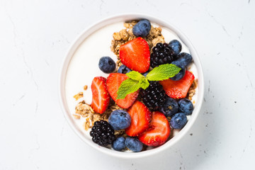 Greek yogurt granola with fresh berries on white table.