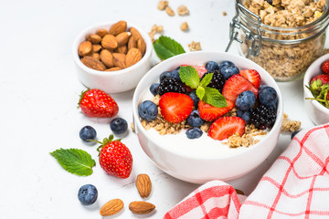 Greek yogurt granola with fresh berries on white table.