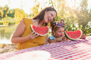 Mother and daughter eating watermelon slice on a picnic