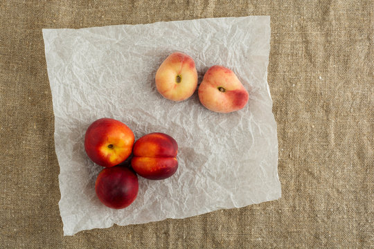 Donut Peaches also known as Saturn peaches and nectarine on a rustic canvas background. Healthy food concept.