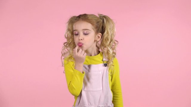 Cute naughty girl making faces on pink background. Slow motion