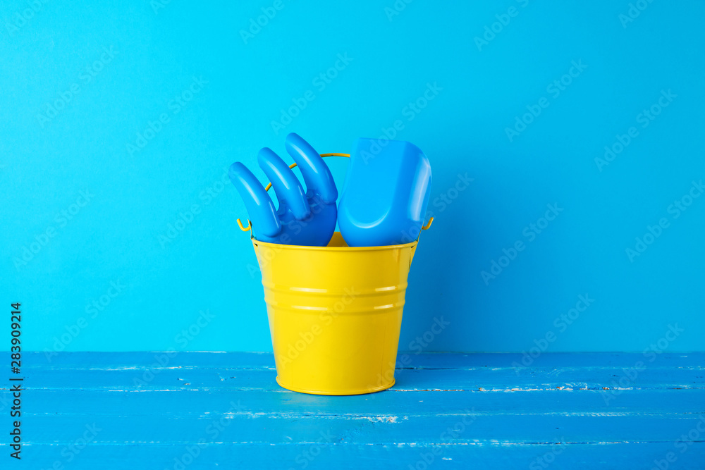 Wall mural yellow children’s metal bucket and plastic shovel and rake