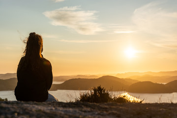 young woman sitting on a mountain just before sunset over the norwegian mountains