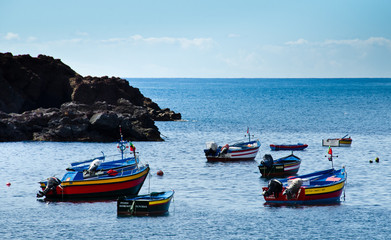 Fototapeta premium Eine Bucht in einem kleinen Fischerort, Camara de Lobos, Madeira, Portugal, Europa, mit vielen bunten Booten, blauem Himmel und stillem Ozean