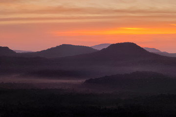 Obraz premium Mountain view morning of Peak mountain above Mekong river around with soft mist and red sun light in the sky background, sunrise at Cha Na Dai Cliff, Pha Taem National Park, Ubon Ratchathani, Thailand