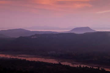 Top view above Mekong river around with mountains, forest, soft mist with red sky background, sunrise at Cha Na Dai Cliff, Pha Taem National Park, Ubon Ratchathani, Thailand.