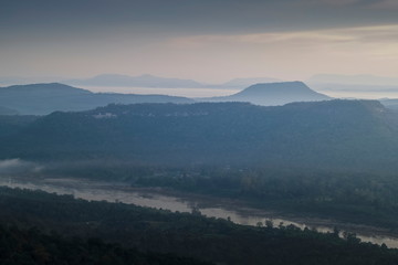 Fototapeta premium Mountain view morning of Peak mountain above mekong river around with soft mist and cloudy sky background, sunrise at Cha Na Dai Cliff, Pha Taem National Park, Ubon Ratchathani, Thailand.