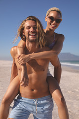 Man giving piggyback ride to woman on the beach