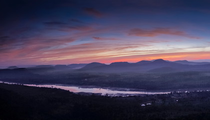 Top view above Mekong river around with mountains, forest, soft mist with red sky background, sunrise at Cha Na Dai Cliff, Pha Taem National Park, Ubon Ratchathani, Thailand.