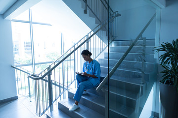 Female surgeon sitting on stairs of hospital