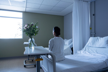 Female patient looking away while sitting on bed
