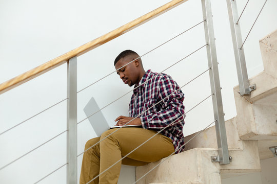 Man working on laptop while sitting on stairs in a comfortable home
