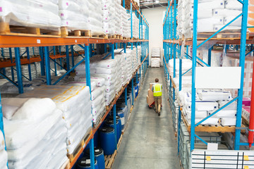Worker carrying boxes on pallet jack in warehouse