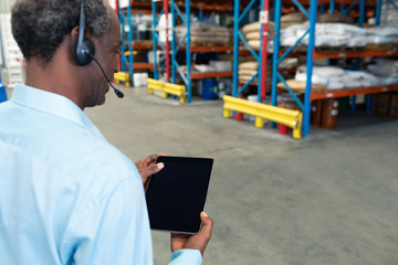 Male supervisor with headset using digital tablet in warehouse