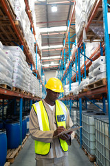 Male worker writing on clipboard in warehouse