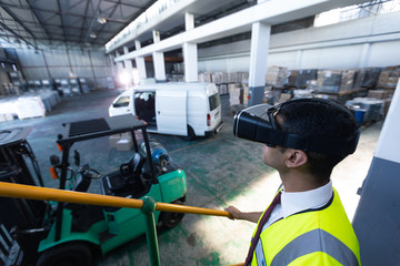 Male supervisor using virtual reality headset in warehouse