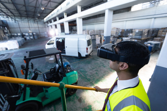 Male supervisor using virtual reality headset in warehouse - Powered by Adobe