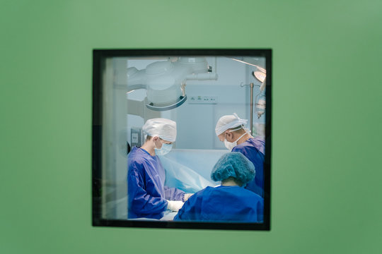 Team surgeon at work in operating room. Modern hospital operating room with surgery in progress.