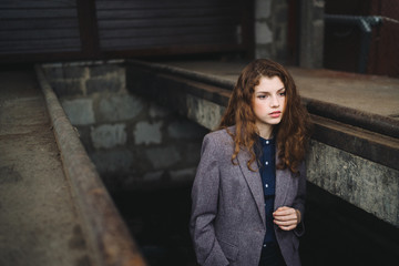 Young beautiful caucasian woman walking in old town. Female art portrait. Stylish girl with long curly red hair.