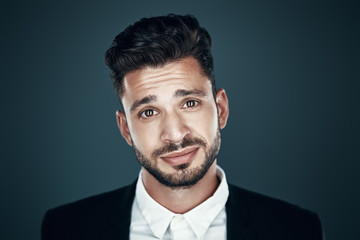 Charming young man in bow tie looking at camera while standing against grey background